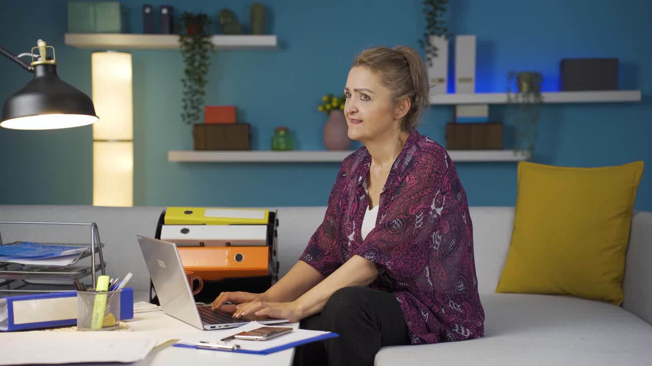 una mujer que trabaja en una oficina se alegra de lo que ve en la computadora portátil.