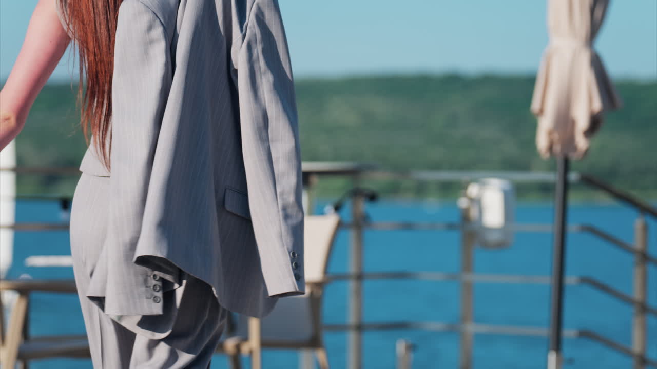 Elegantly dressed man and woman walking on a scenic terrace with a view of a calm body of water