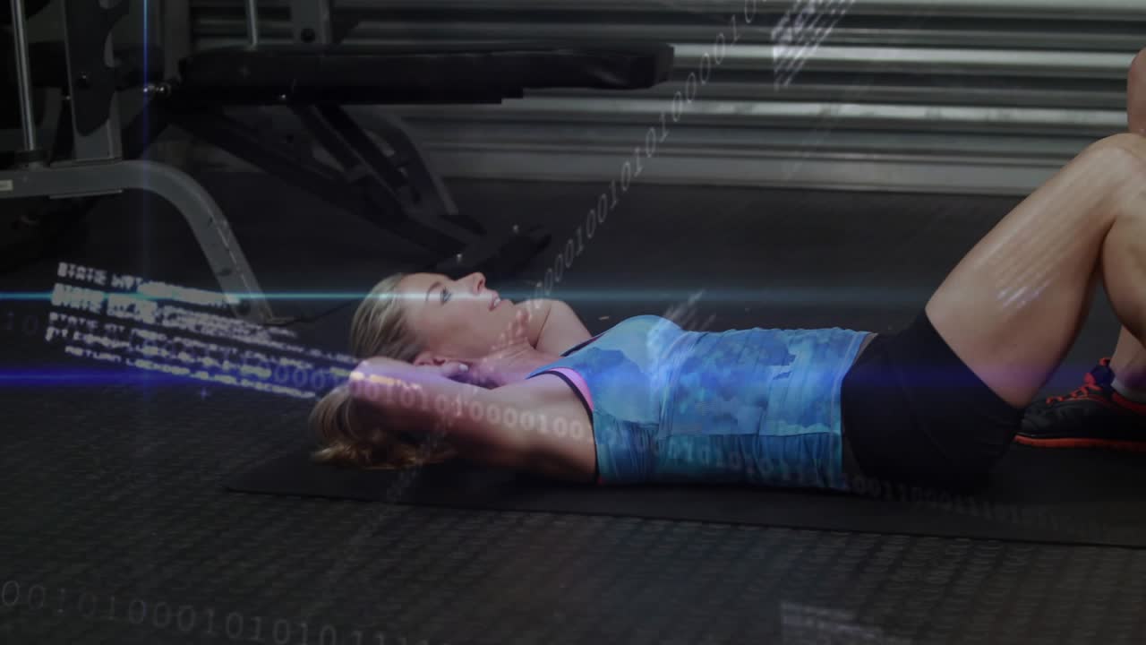 Woman starting crunches on mat in gym, man kneeling holding feet for support, data overlay sweeping