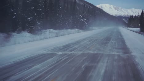 pov shot driving on icy road, in middle of frosty forest and arctic nature, passing a oil truck, at dusk, in alaska, usa