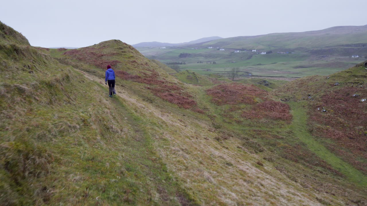 снимок счастливой девушки, идущей по туристической тропе в сказочном глене в шотландии, остров скай