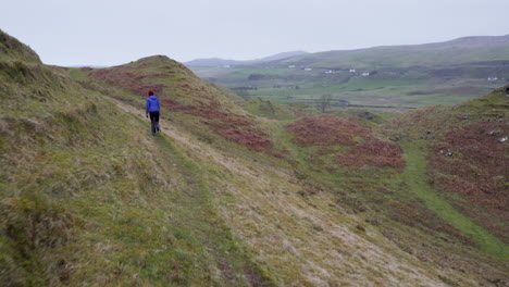 Tracking-follow-shot-of-happy-girl-walking-on-the-hiking-trail-at-Fairy-Glen-in-Scotland,-Isle-of-Skye