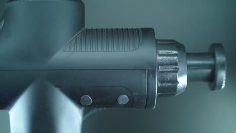 A-close-up-shot-of-a-massage-muscle-gun,-vibration-tool,-slow-motion-Full-HD-video,-studio-lighting,-black-plastic-head