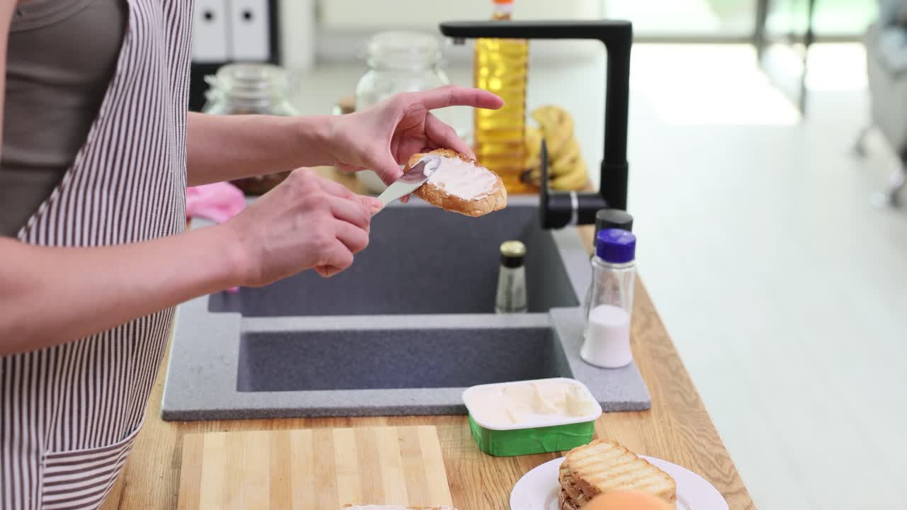 Woman spreading butter on toast in the kitchen