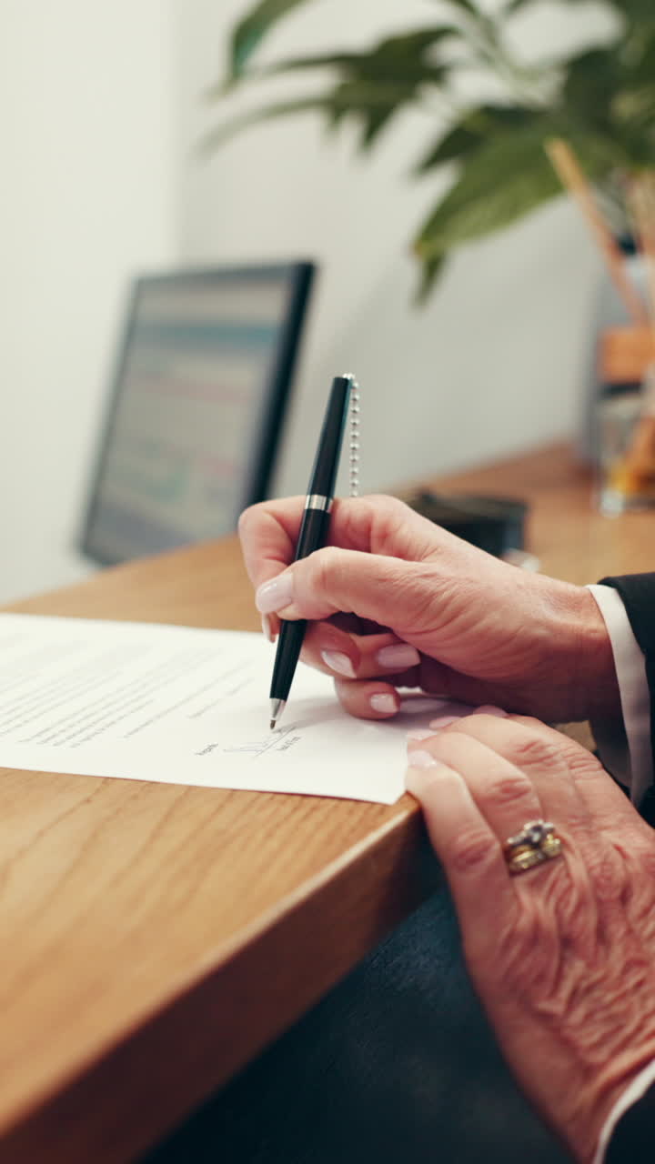 Primo piano di mani che firmano un documento con una penna su una scrivania di legno