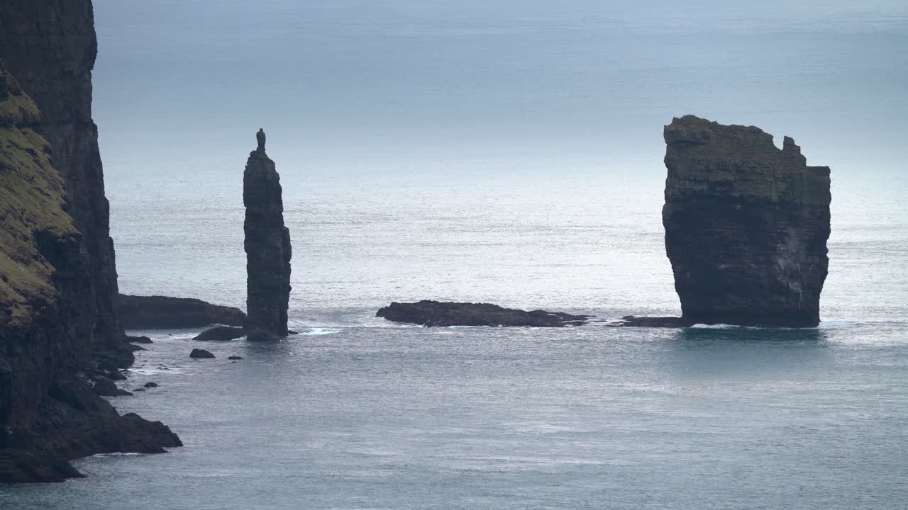 tiro medio estático de pilas de mar risinn og kerlingin en la isla de eysturoy durante el día nublado místico, 4k - islas feroe, dinamarca