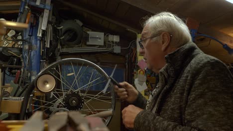 pensive senior caucasian mechanic arranges tools in a a dark workshop