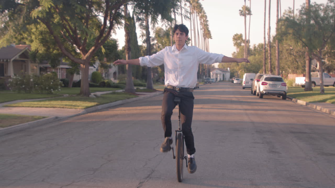 Man riding a unicycle down a suburban street