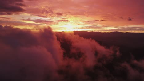 Cielo-Rojo-Brillante-Y-Sol-Al-Atardecer-Con-Niebla-Y-Nubes-Esponjosas-En-Primer-Plano,-Dron-De-4k