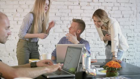 business leader is sitting at the table and explaning something to employee on laptop. coworkers team discussion business project using laptop