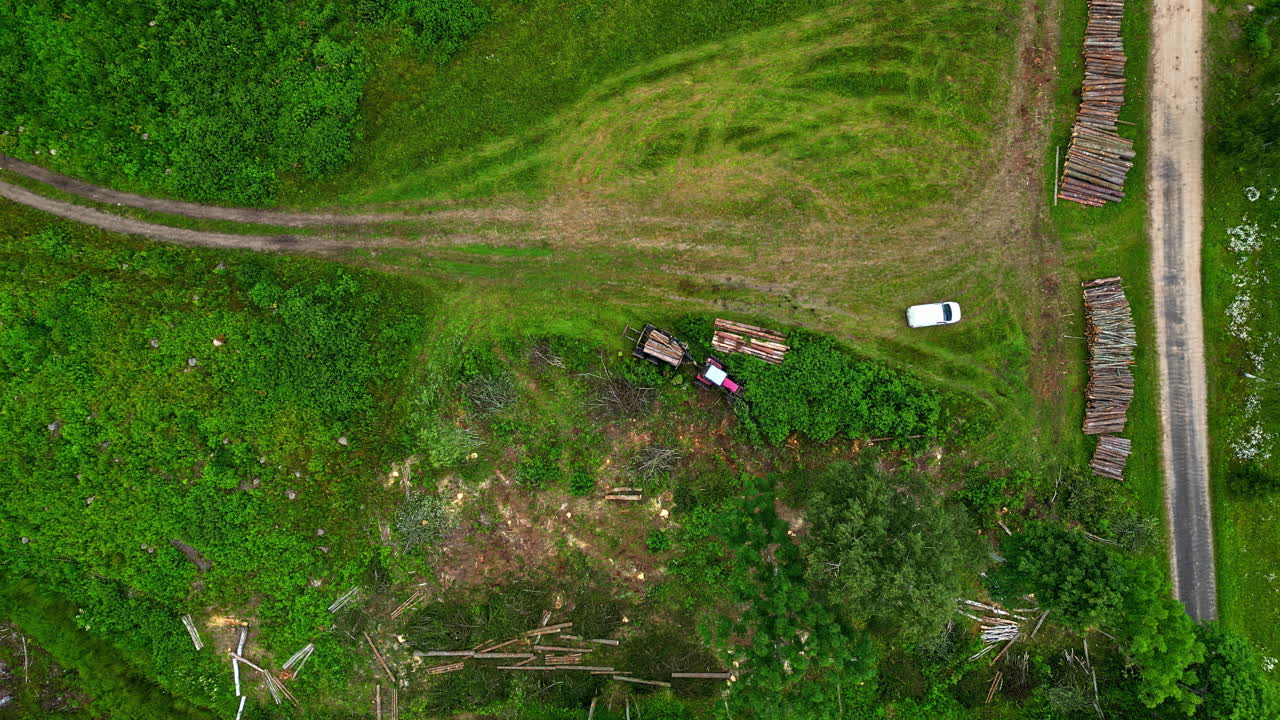 remolque de tractor cargador de troncos apilando madera a lo largo de un camino forestal - vista aérea hacia abajo