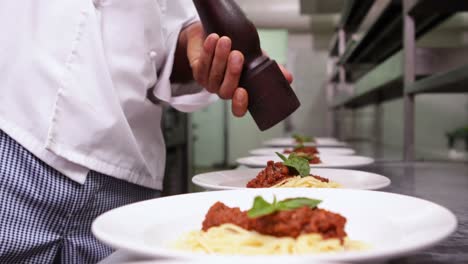 chef aderezando cenas de espagueti con pimienta negra