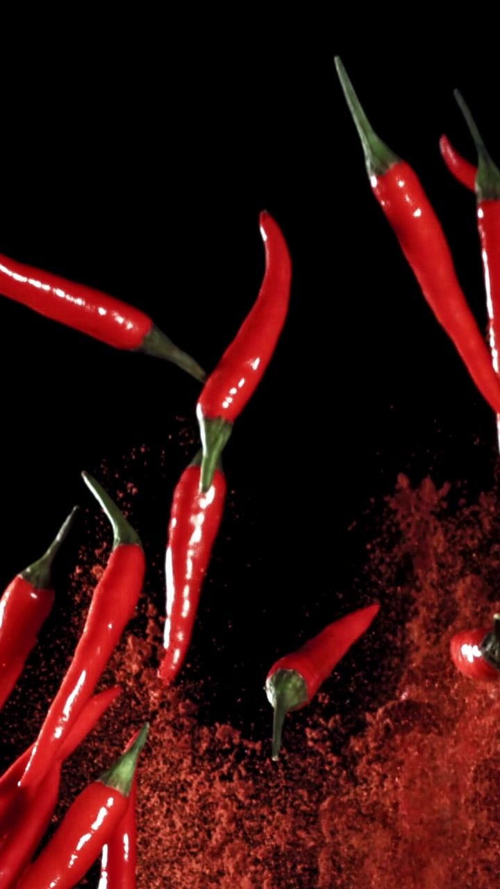 Vibrant Red Chili Peppers and Powder Falling Against Black Background