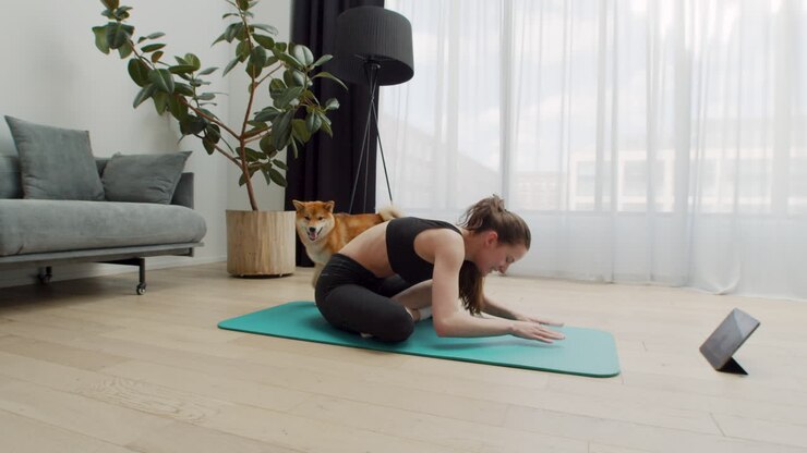 Una giovane donna bellissima fa yoga a casa mentre il suo cane le gira intorno