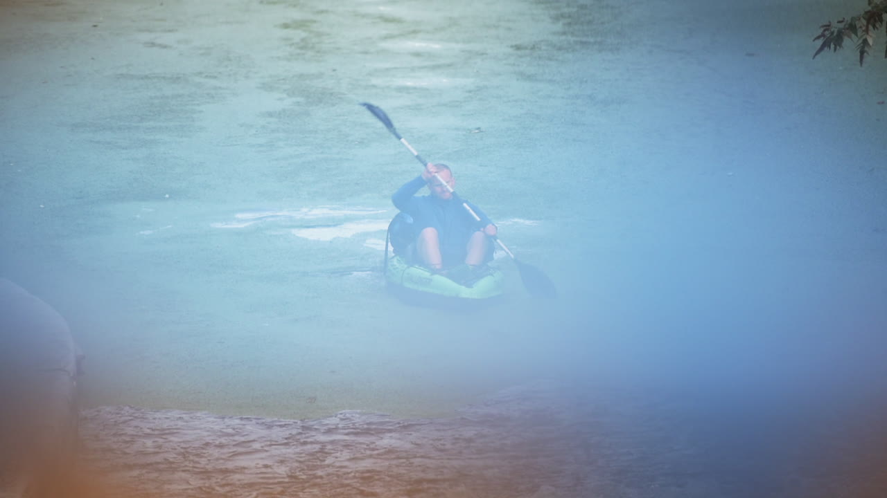 A man paddles a kayak down the waterways in London at a calm relaxing pace in the cool blue surroundings