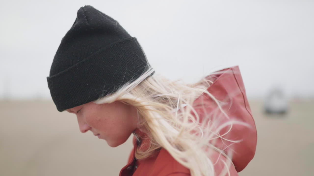 바람이 네덜란드 muiden에서 그녀의 금발 머리를 날리는 동안 검은 비니와 빨간 후드 재킷을 입고 어린 소녀