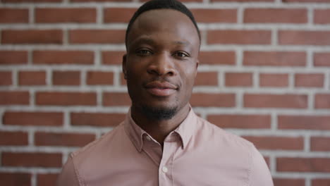 portrait confident young african american businessman looking calm at camera independent black male entrepreneur on brick wall background