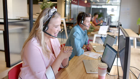 Happy-caucasian-casual-businesswoman-and-diverse-colleagues-using-phone-headsets,-slow-motion