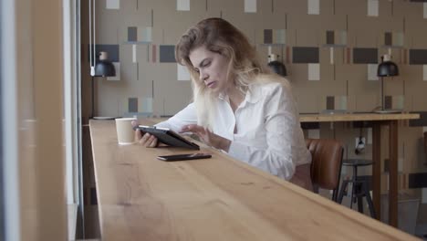 gerente femenina enfocada usando tableta mientras está sentada en el escritorio