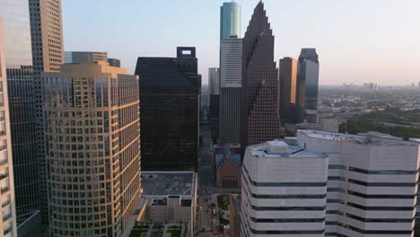 Vista-Aérea-Volando-En-Medio-De-Edificios-En-La-Calle-Louisiana,-Amanecer-En-El-Centro,-Houston