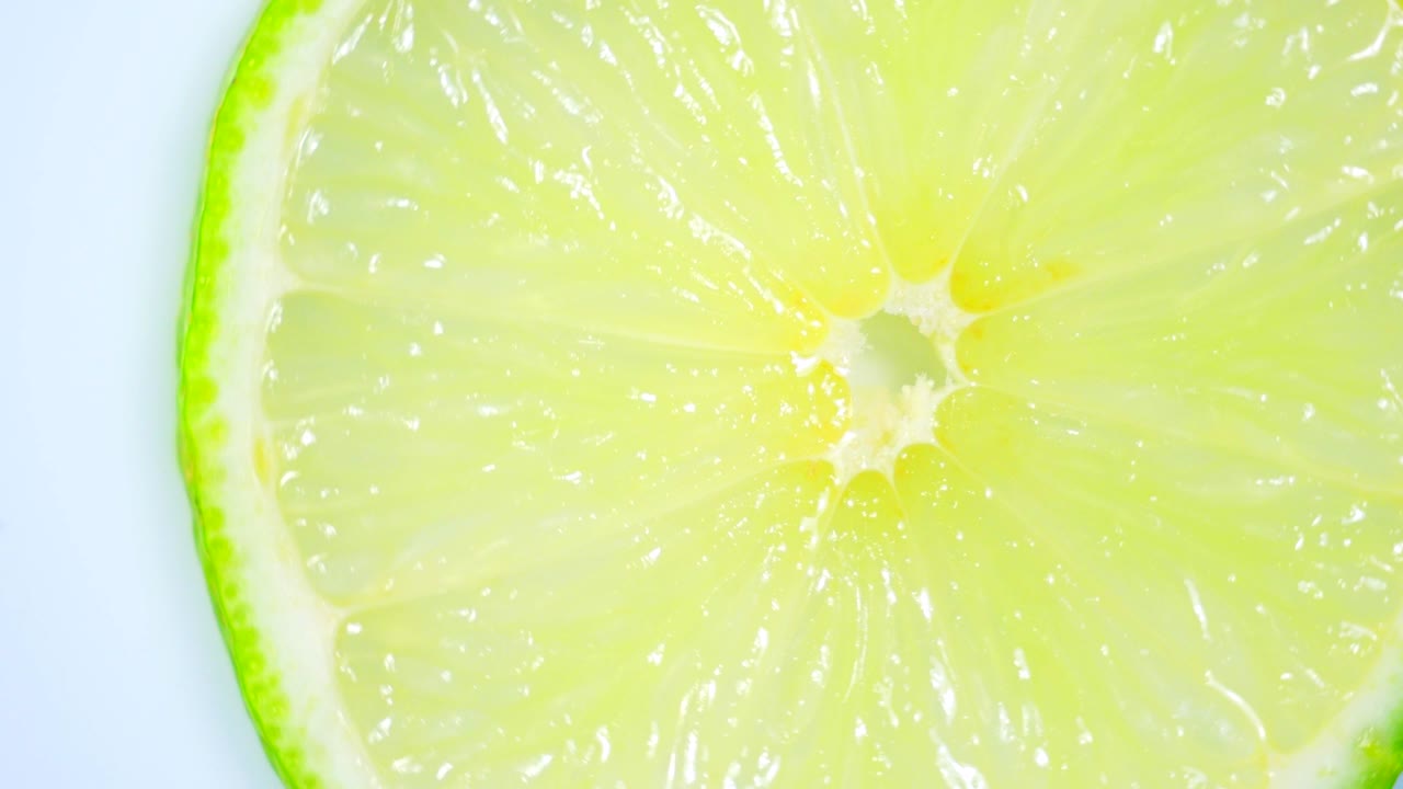 una rebanada de limón verde está girando lentamente en el estudio con los detalles.