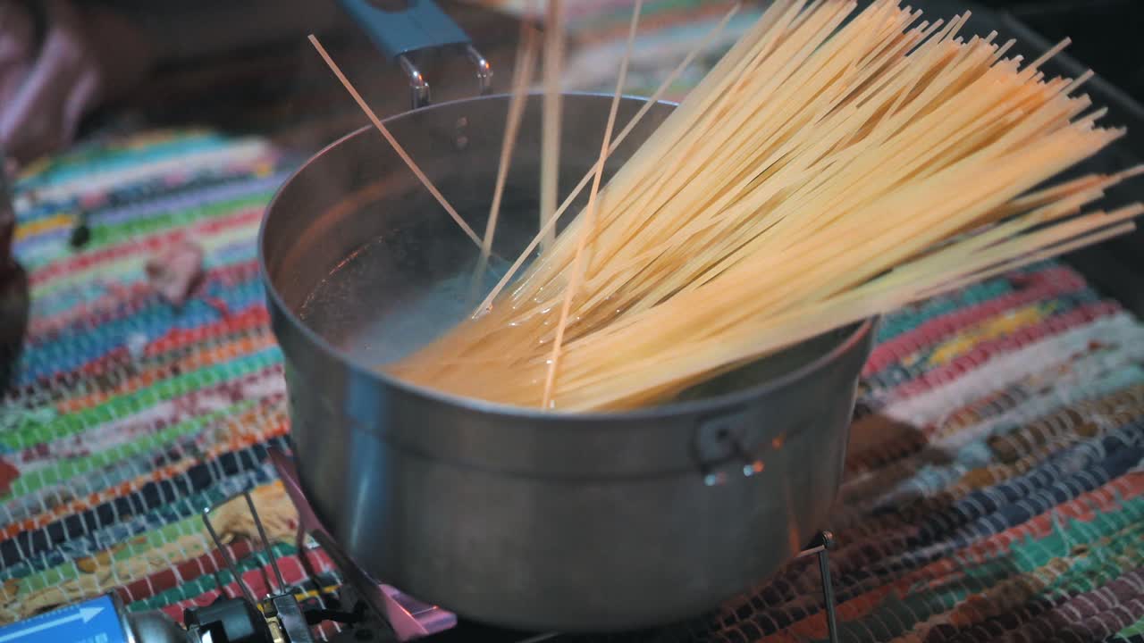 cocinar pasta con una estufa de gas portátil en una cabaña en la naturaleza, al aire libre, acampar