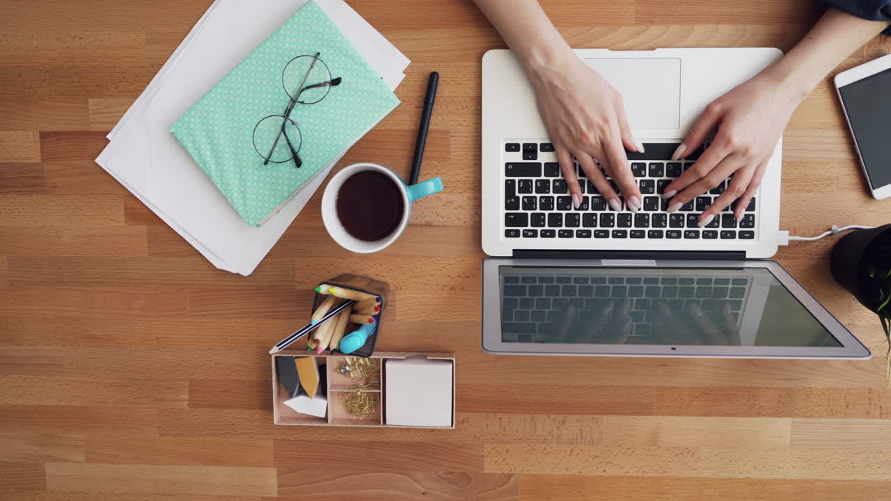Overhead view of a woman working on a laptop at a wooden desk