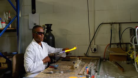 side view of black male worker blowing glass in glass factory 4k