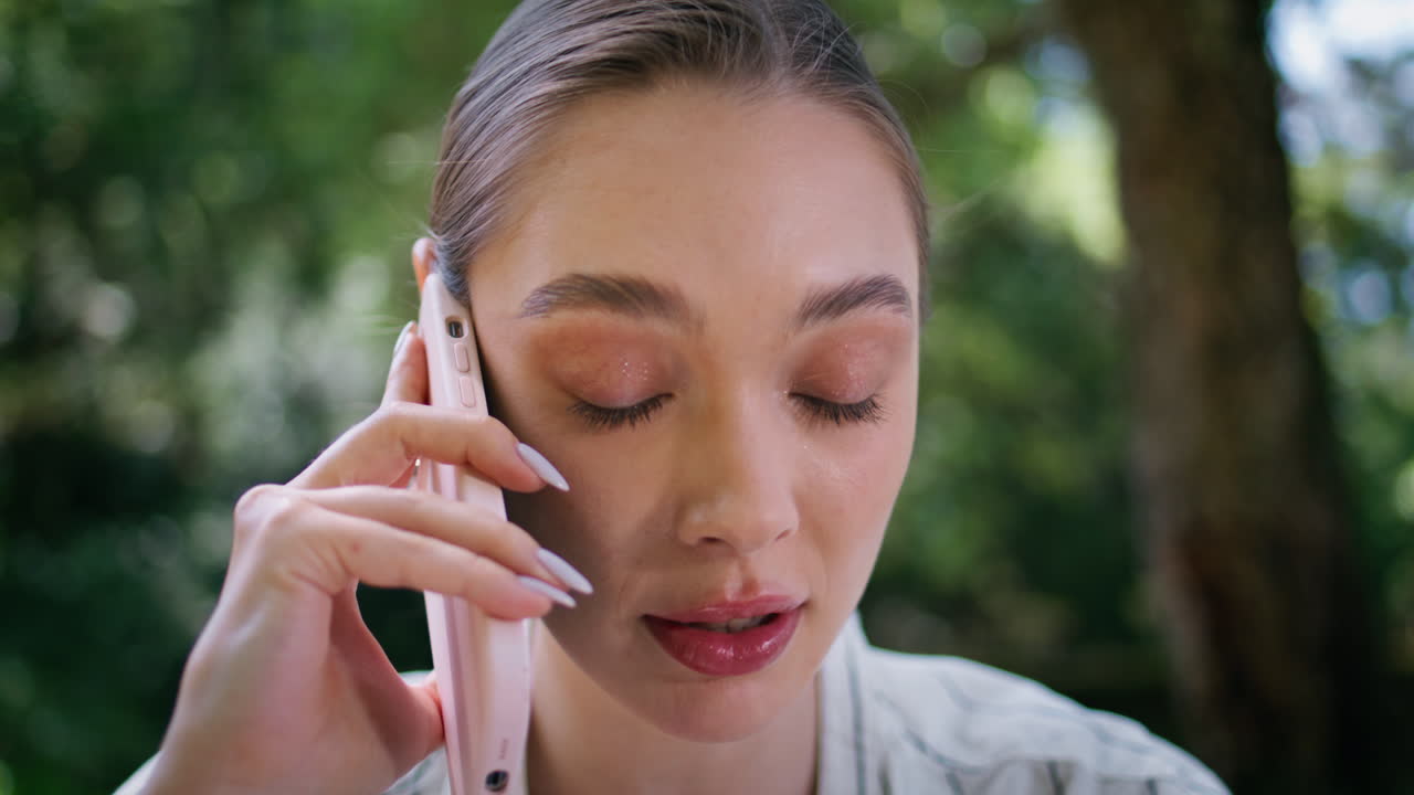 una mujer de negocios atractiva hablando por teléfono de pie en el parque verde sola de cerca.