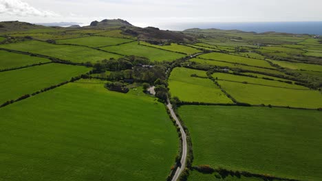 verdant meadows of english countryside and sea in background, aerial forward