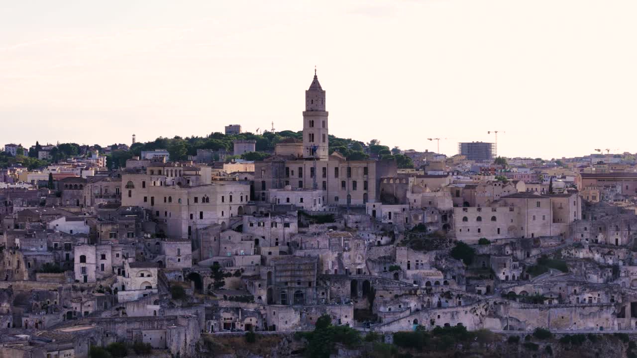 Wieża kościoła i centrum miasta Matera, słońce świeci zza niej, widok z lotu ptaka