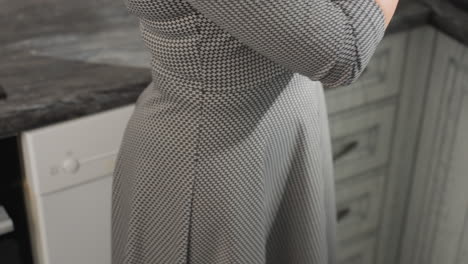 lower body view of woman in plaid patterned gown standing close to kitchen cabinet, focused and busy with task, bright modern kitchen background