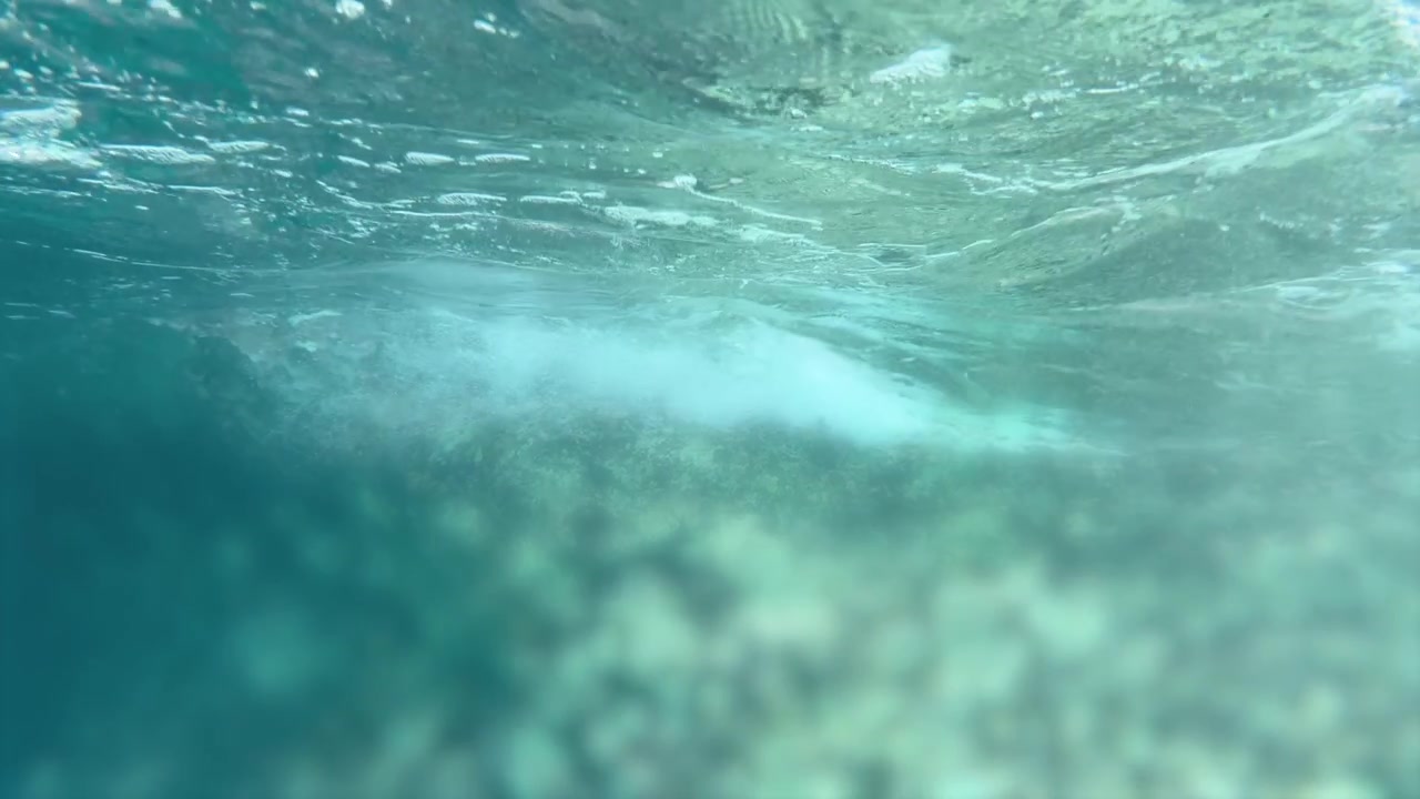 L'acqua cristallina turchese dell'oceano rivela una vivace barriera corallina con la luce del sole che luccica attraverso la superficie.
