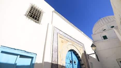 white walls and blue accents of a traditional building under clear skies in tunisia's old city