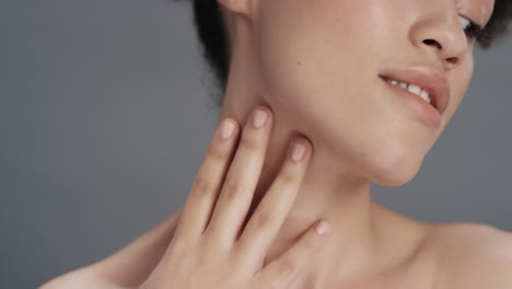 close up portrait beautiful mixed race woman touching soft skin with hand caressing smooth healthy complexion enjoying natural skincare gorgeous feminine beauty concept on grey background