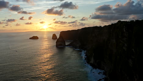 Barco-Navegando-Bajo-Los-Acantilados-De-Nusa-Penida-Al-Atardecer,-Bali-En-Indonesia