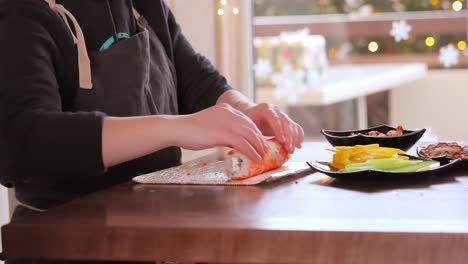 making sushi at home kitchen. woman hands rolling homemade sushi.