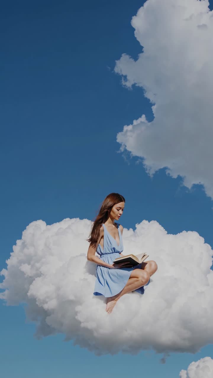 Aerial view of a woman in a blue dress reading on a fluffy cloud against a clear sky