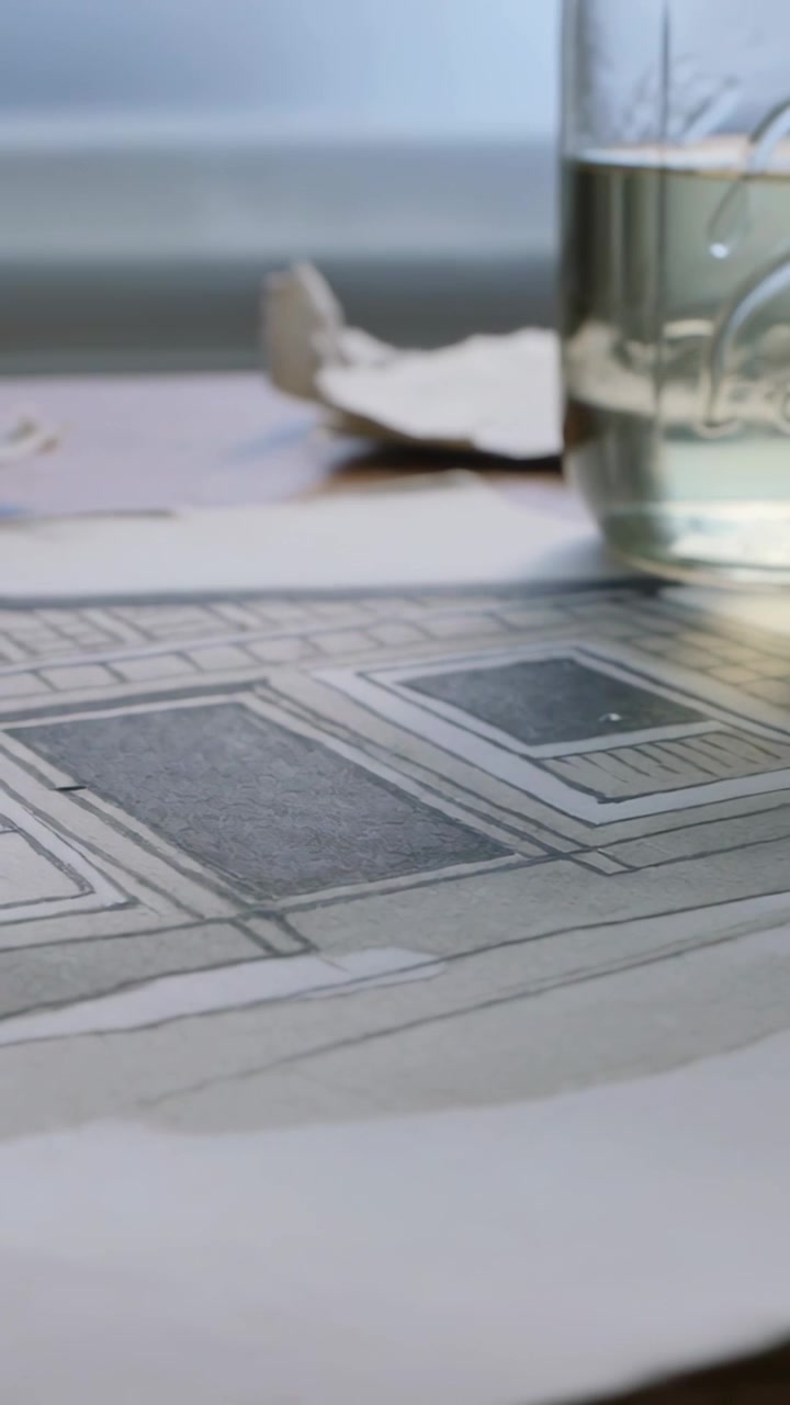 Vertical video: Shifting camera showing rectangle drawing on art table by window, jar