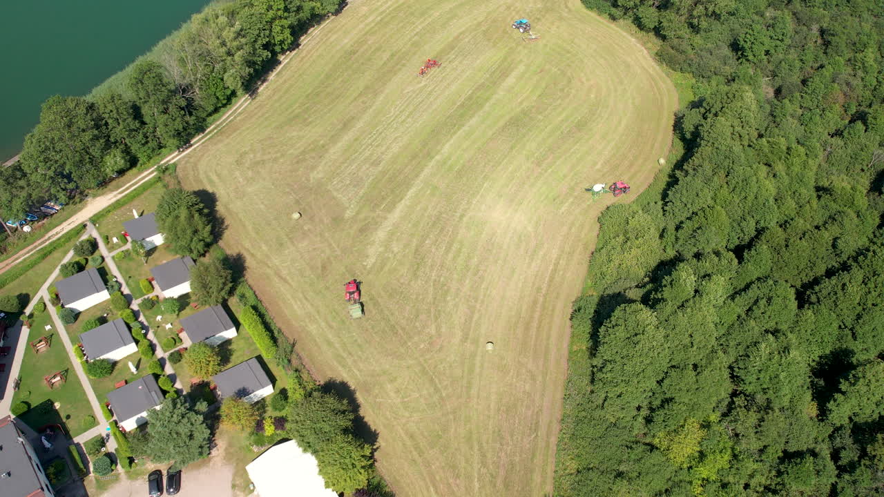 폴란드 chmielno에 있는 들판에서 건초를 모으는 두 개의 트랙터의 공중 하향식 전망