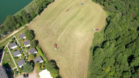 aerial top down view of two tractors collecting hay in field in chmielno, poland