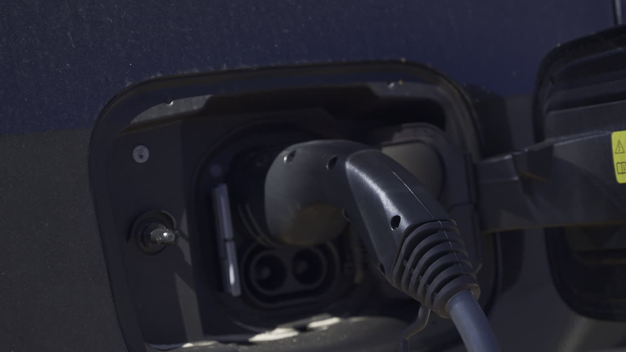 Close up of an electric car charger plugged into a black car