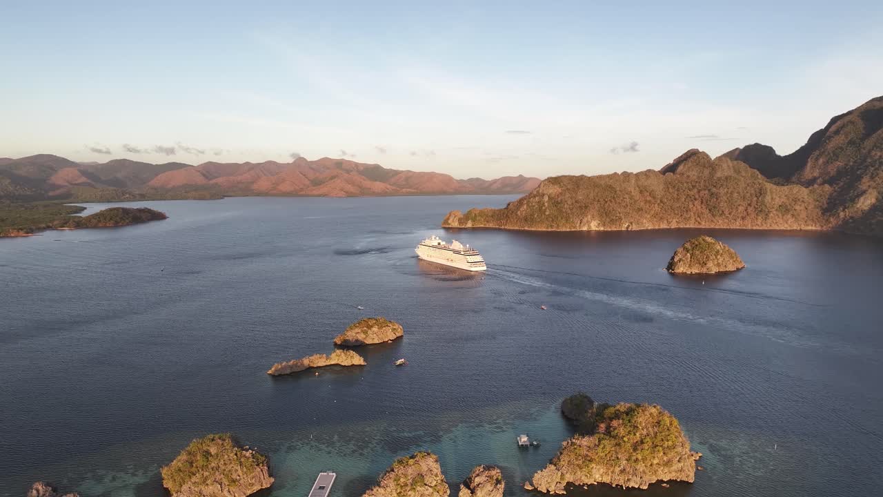 Cruise Ship Navigating On Calm Waters Surrounded By Limestone Cliffs In Coron, Palawan, Philippines. wide aerial shot