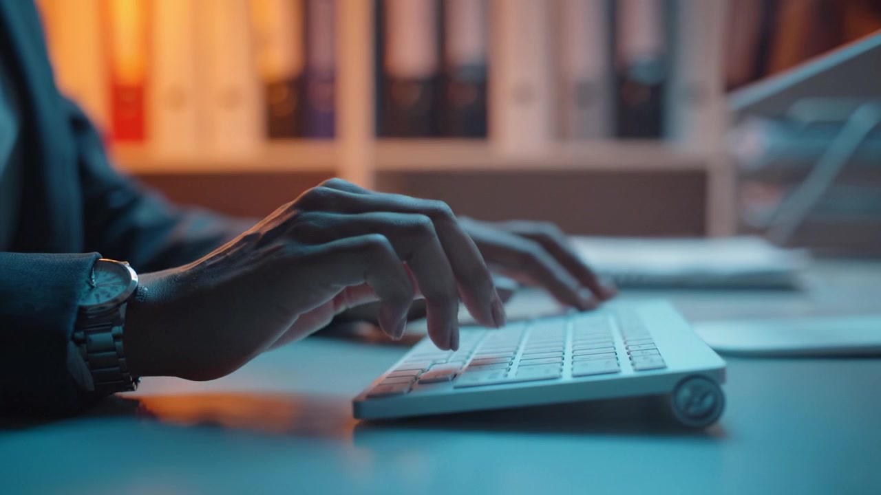 Focused Hands Typing on a Modern Keyboard in a Well-Organized Office Environment, Illuminated by Soft Ambient Lighting for a Productive Atmosphere