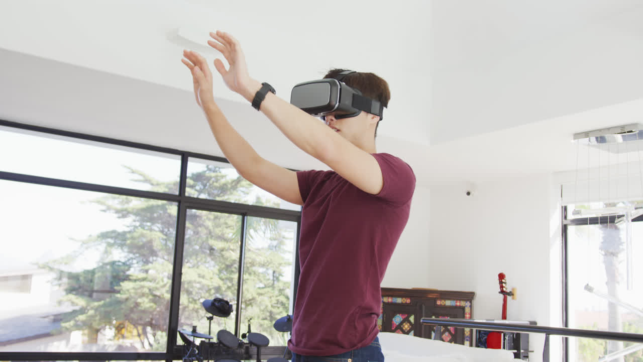 Asian boy wearing vr headset gesturing in living room at home