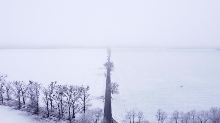 Rural crossroads between snow-covered fields and meadows on a sunless hazy morning