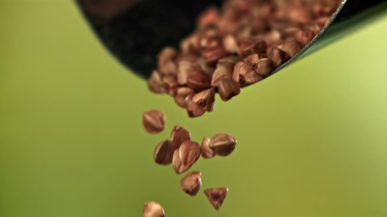 Chicchi di grano saraceno che cadono da un mestolo al rallentatore