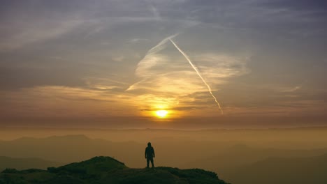 the man standing on a mountain on the bright sunset background