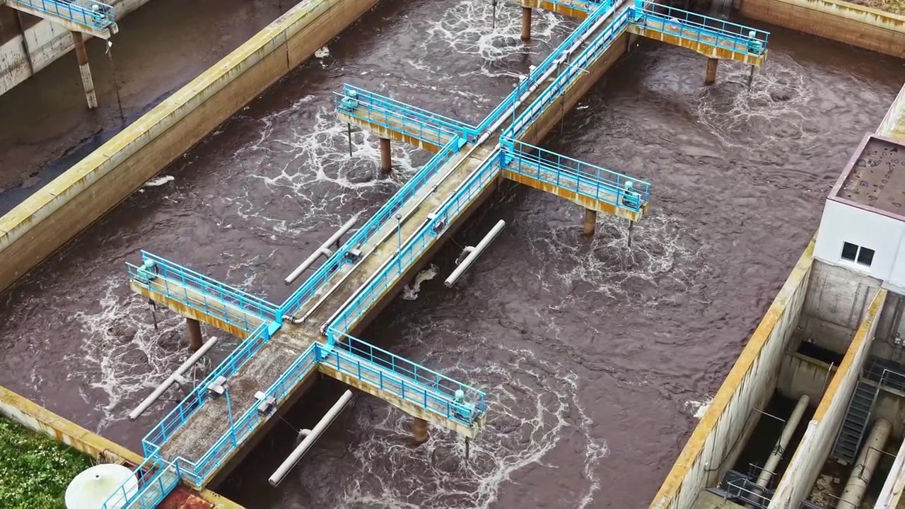 Workers manage wastewater in a treatment facility during daylight hours in an urban area