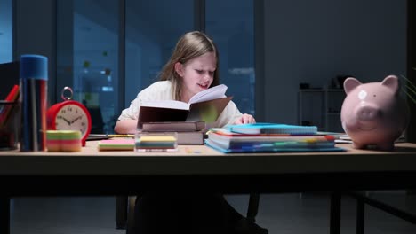 young girl diligently studying books at night